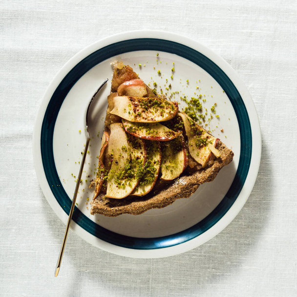 italian apple pie crostata with pistachio crumbs on the table with a white tablecloth - Fotó, kép