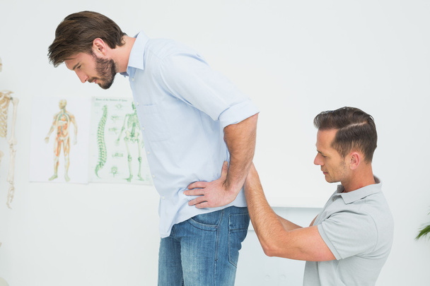 Side view of a male physiotherapist examining man's back - Zdjęcie, obraz