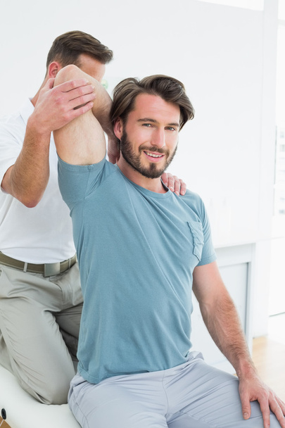 Male physiotherapist stretching a young man's arm - Photo, image