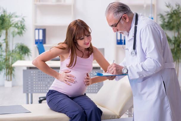 Jonge zwangere vrouw bezoekt oude mannelijke arts gynaecoloog - Foto, afbeelding
