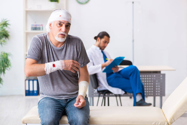 Young male doctor and old patient in first aid concept - Photo, Image