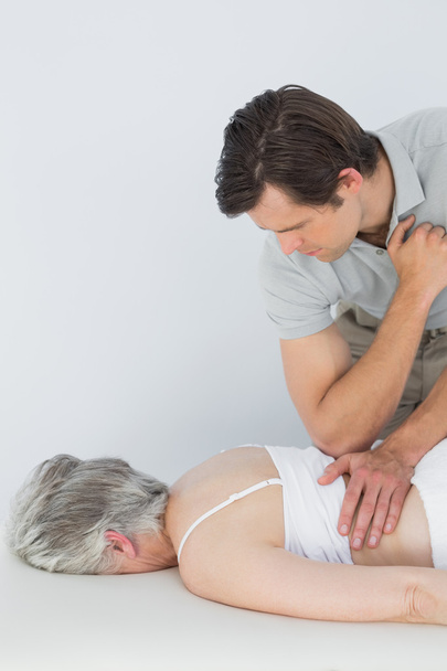 Male physiotherapist massaging a senior woman's back - Foto, afbeelding