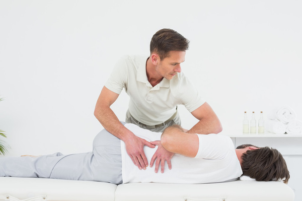 Male physiotherapist examining man's back - Foto, afbeelding