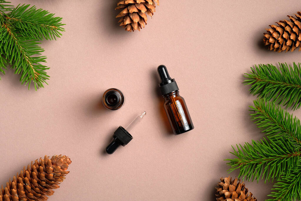 Flat lay composition with dropper bottles of conifer essential oil. Natural organic cosmetics with pine branches and cones. Top view. - Foto, afbeelding