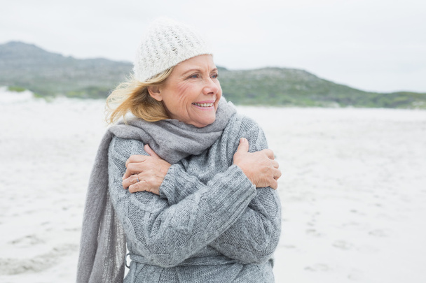 Cheerful senior woman shivering at beach - Foto, imagen