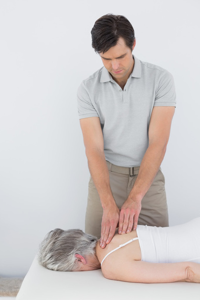 Male physiotherapist massaging a senior woman's back - Foto, Imagen