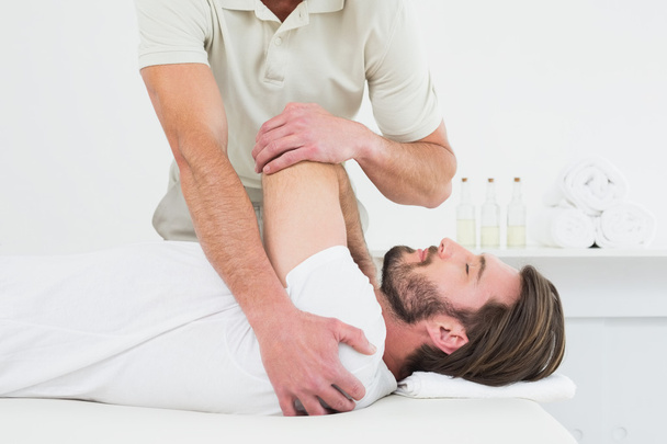 Male physiotherapist stretching a young man's hand - Foto, Imagen