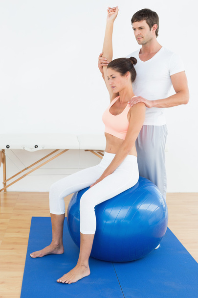 Woman on yoga ball while working with physical therapist - Φωτογραφία, εικόνα