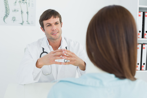Doctor listening to patient with concentration in medical office - Photo, image