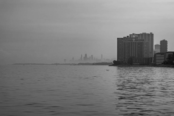 Panoráma fekete-fehér városkép fénykép a chicagói városkép homályos és köd borítja egy forró nyári napon, és nyugodt Michigan-tó előtérben kilátás Loyola strand. - Fotó, kép