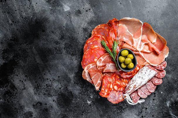 Spanish cold meat assortment. Chorizo, fuet, LOMO, jamon Iberico, olives. Black background. Top view. Copy space. - Φωτογραφία, εικόνα