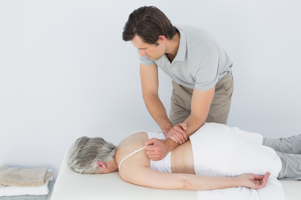 Male physiotherapist massaging a senior woman's back - Фото, зображення