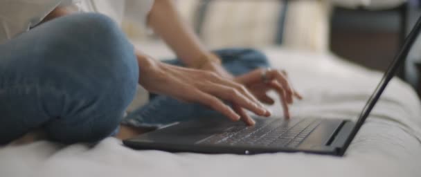 Egy nő keze gépel valamit egy laptop billentyűzetén a hálószobában. Lassú mozgás, sekély mélységélesség, BMPCC 4K - Felvétel, videó