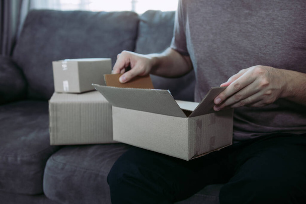 Asian entrepreneur teenager is opening a cardboard box in order to put the product that the customer ordered into the box to deliver the product. - 写真・画像