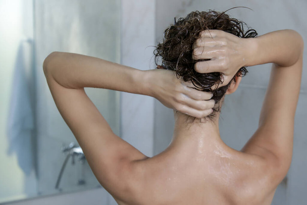 Haarshampoo und Kopfhautmassage. Rückansicht einer Frau in der Duschkabine. - Foto, Bild