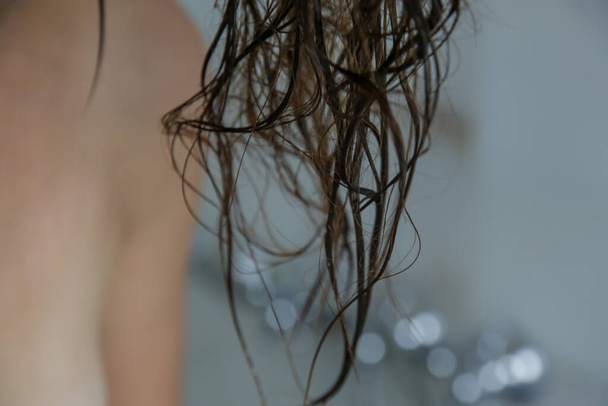 Woman applaying conditioner on her wet tangled hair in the shower cabin. - 写真・画像