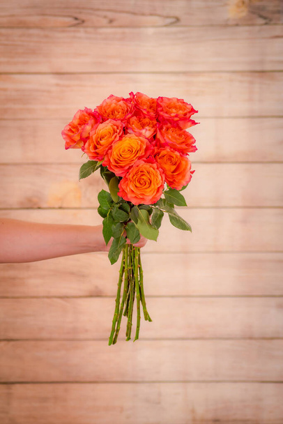 Women hand holding a bouquet of Free Spirit roses variety, studio shot, orange flowers - Фото, зображення