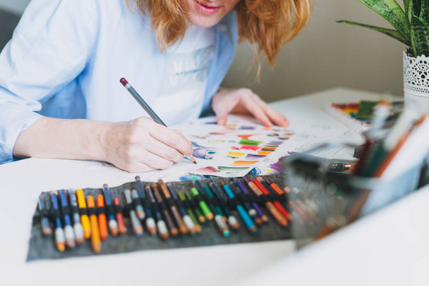 Schnitte Foto von junger Frau mit roten Haaren Illustrator Künstler zeichnet am Schreibtisch zu Hause im Büro - Foto, Bild