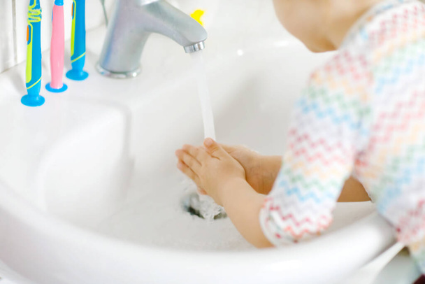 Close-up de menina pequena criança lavar as mãos com sabão e água no banheiro. Fechar crianças aprendendo a limpar partes do corpo. Ação de rotina de higiene durante a doença viral. criança em casa ou berçário. - Foto, Imagem