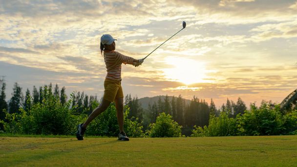 Golfer sport course golf ball fairway.  People lifestyle woman playing game golf tee of on the green grass sunset background.  Asia female player game shot in summer. Healthy and Sport outdoor - Φωτογραφία, εικόνα