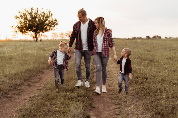 Uma família feliz está desfrutando e caminhando no campo. Mãe, pai, dois filhos. Caminhadas durante as férias
. - Foto, Imagem