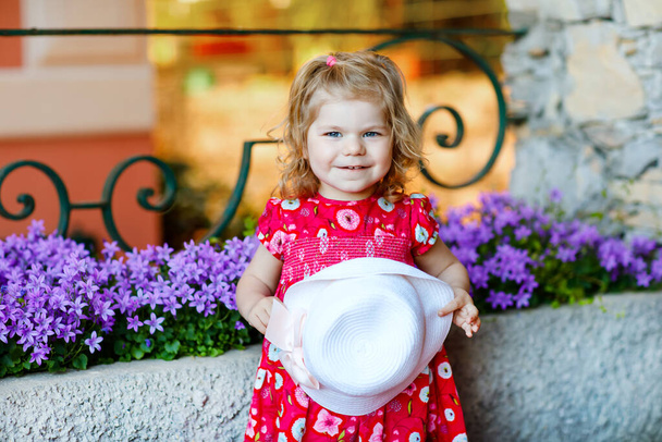 Pembe elbiseli, moda elbiseli, diz altı çoraplı ve şapkalı güzel küçük bir kız çocuğunun portresi. Renkli evin önünde poz veren mutlu sağlıklı bebek.. - Fotoğraf, Görsel