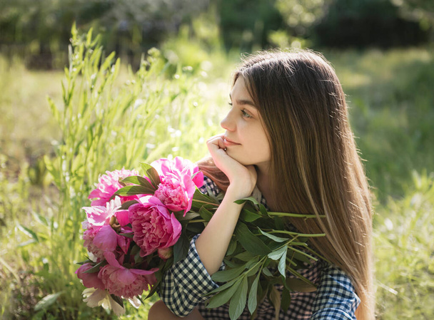 Portrait d'une belle fille avec un bouquet de pivoines. - Photo, image
