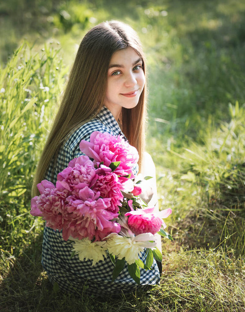 Portrait of a beautiful girl with a bouquet of peonies. - Foto, Imagen