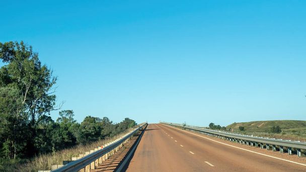 Запечатанное шоссе в австралийской глубинке, не имеющее других транспортных средств в поле зрения
 - Фото, изображение