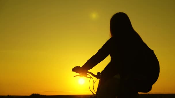 μοναχική ποδηλάτισσα που ξεκουράζεται στο πάρκο. Πεζοπόρος υγιής νεαρή γυναίκα στέκεται στο λόφο δίπλα σε ένα ποδήλατο, απολαμβάνοντας τη φύση και τον ήλιο. Το ελεύθερο κορίτσι ταξιδεύει με ποδήλατο το ηλιοβασίλεμα. έννοια της περιπέτειας και των ταξιδιών. - Πλάνα, βίντεο