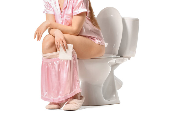 若い女性は白い背景を背景にトイレのボウルに座って - 写真・画像