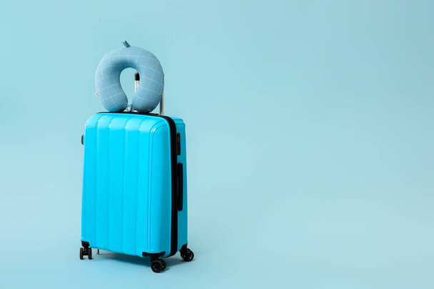 Packed suitcase and travel pillow on color background - Φωτογραφία, εικόνα