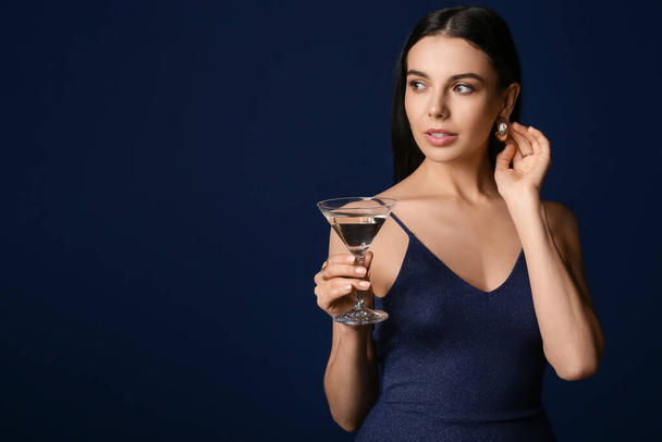 Kaunis nuori nainen, jolla on martini tummalla taustalla - Valokuva, kuva