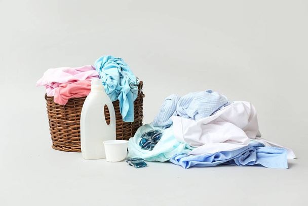 Basket with dirty clothes and detergent on light background - Photo, Image