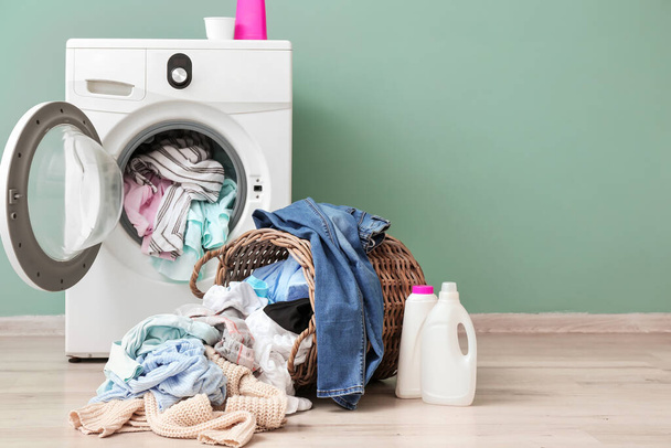Wasmachine met vuile kleren in de buurt van kleur muur - Foto, afbeelding
