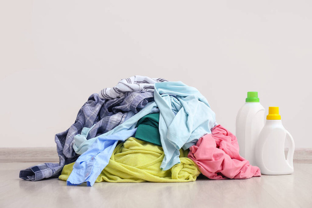 Schmutzige Wäsche auf dem Fußboden in der Nähe einer Lichtwand - Foto, Bild