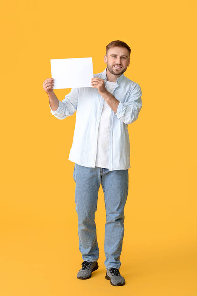 Young man with blank card on color background - Fotoğraf, Görsel