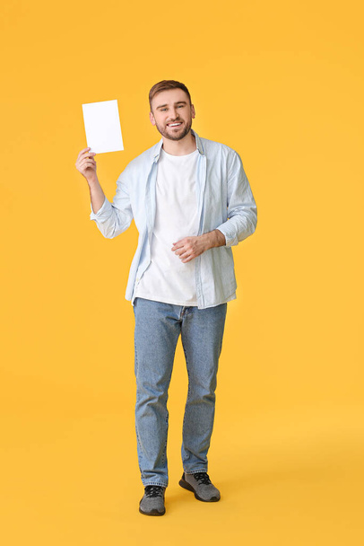 Νεαρός άνδρας με λευκή κάρτα στο φόντο χρώμα - Φωτογραφία, εικόνα