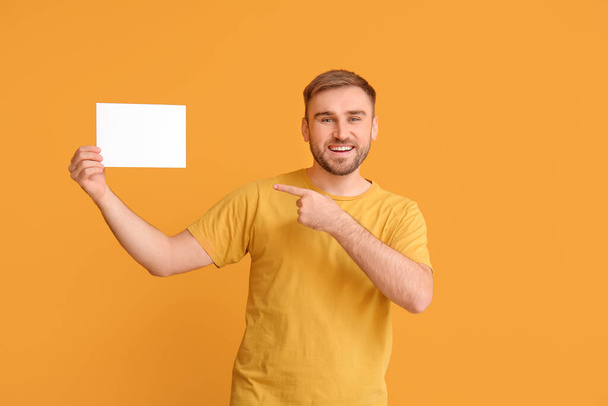 Young man with blank card on color background - Фото, изображение