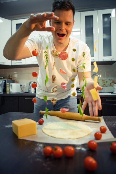 man making pizza ingredients like salami mushrooms olive cheese freeze in air. home cooking - Photo, Image