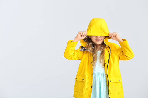 Cute little girl in raincoat on grey background - Valokuva, kuva