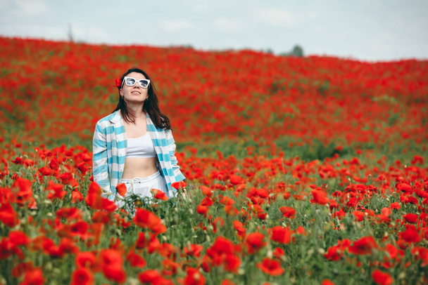 joven mujer bonita en gafas de sol en el campo de las flores de amapola. espacio de copia. hora de verano - Foto, imagen