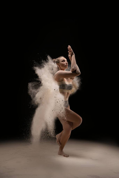 Fit female dancing in cloud of dust - Foto, afbeelding