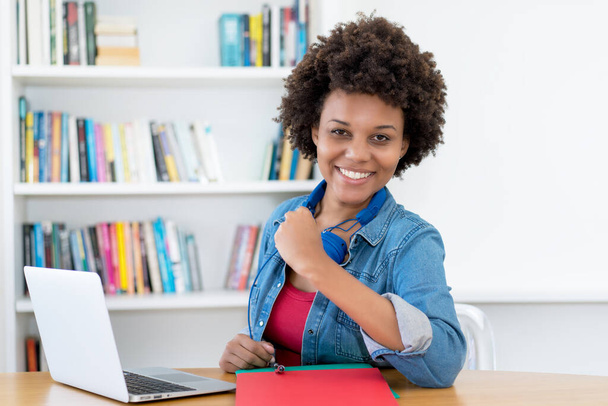 Happy african american young adult woman at computer indoors at desk at home - Foto, Imagem