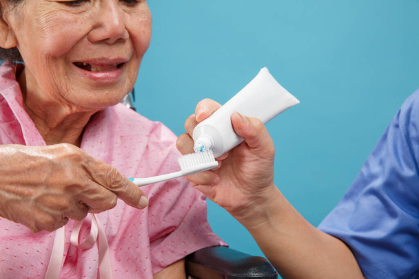 Caregiver take care asian elderly woman while using toothbrush. - Фото, зображення