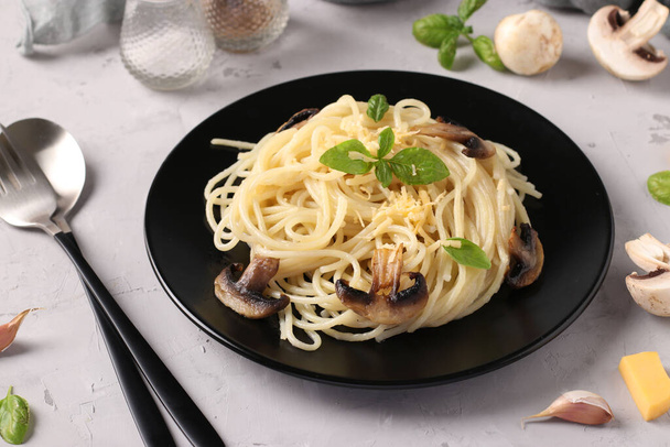 Spaghettis aux champignons et basilic sur plaque noire sur fond gris, Gros plan - Photo, image