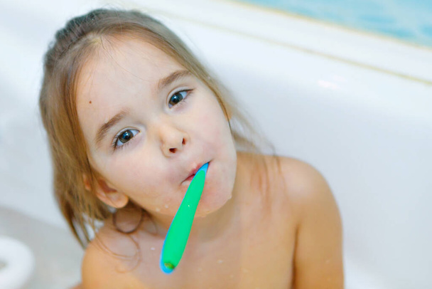 a little girl brushes her teeth in the bathroom. portrait of a child with a toothbrush - Foto, immagini