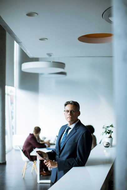 Schöner Geschäftsmann mit digitalem Tablet im Büro - Foto, Bild