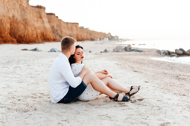 Kochająca para w białych ciuchach podczas miesiąca miodowego na morzu spacer po piasku na sesji zdjęciowej Love Story, wybrzeże oceanu, plaża - Zdjęcie, obraz