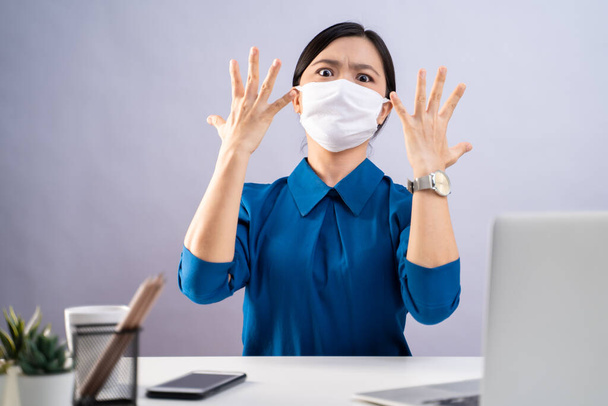 Don't Touch Your Face. Asian woman in blue shirt wearing protective face mask, showing hand making stop sign, working on a laptop sitting at office. isolated on white background. - Foto, afbeelding